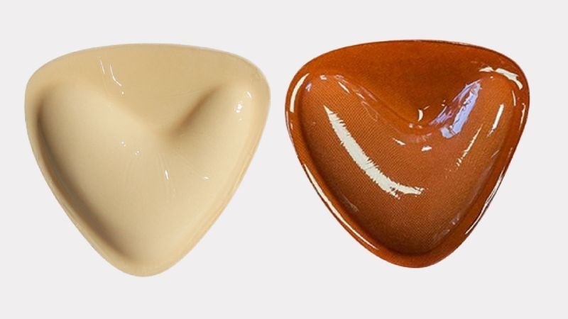Two triangular breast enhancer inserts with molded contoured shapes and glossy surfaces