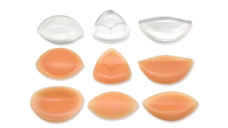Assorted clear and skin-tone silicone breast enhancer inserts in multiple shapes and sizes