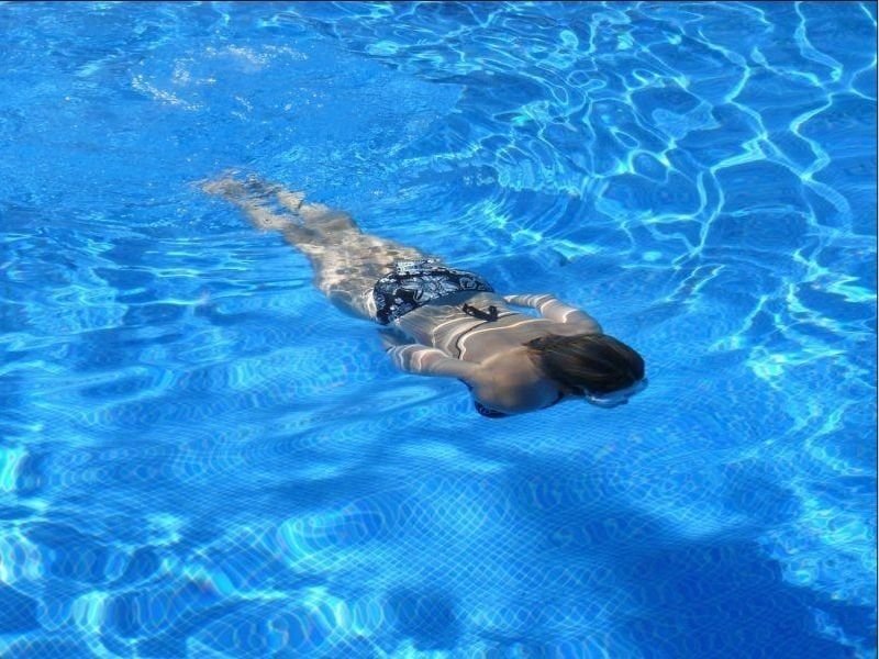 A girl in a swimsuit is swimming in the pool.